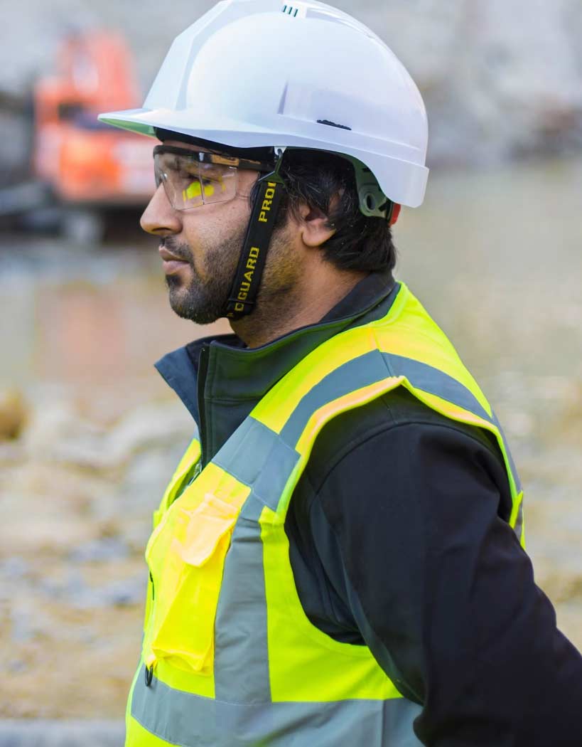 Man Using Measuring Tape in Factory Setting